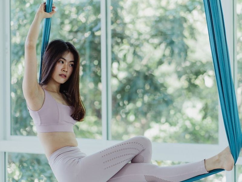 Person performing a flowing yoga movement in a bright studio.